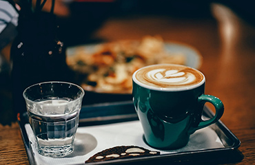 a tray with a cup of coffee and a glass of water